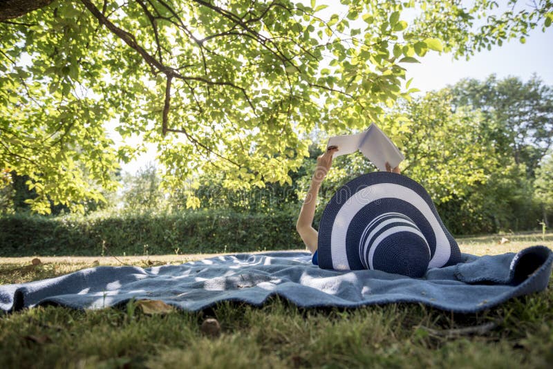 Woman wearing a straw hat in summer nature reading a book royalty free stock photos Woman wearing a straw hat in summer nature reading a book royalty free stock photos