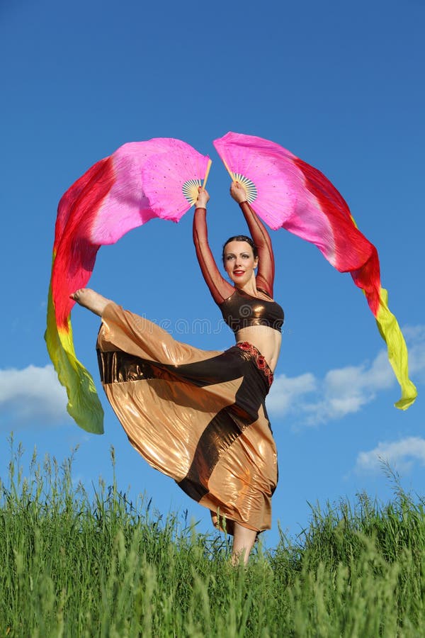 Woman wearing suit dances with pink veil fans