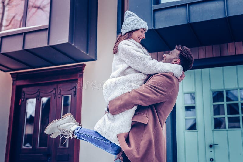 Woman wearing warm beige coat jumping into hands of husband royalty free stock images Woman wearing warm beige coat jumping into hands of husband royalty free stock images