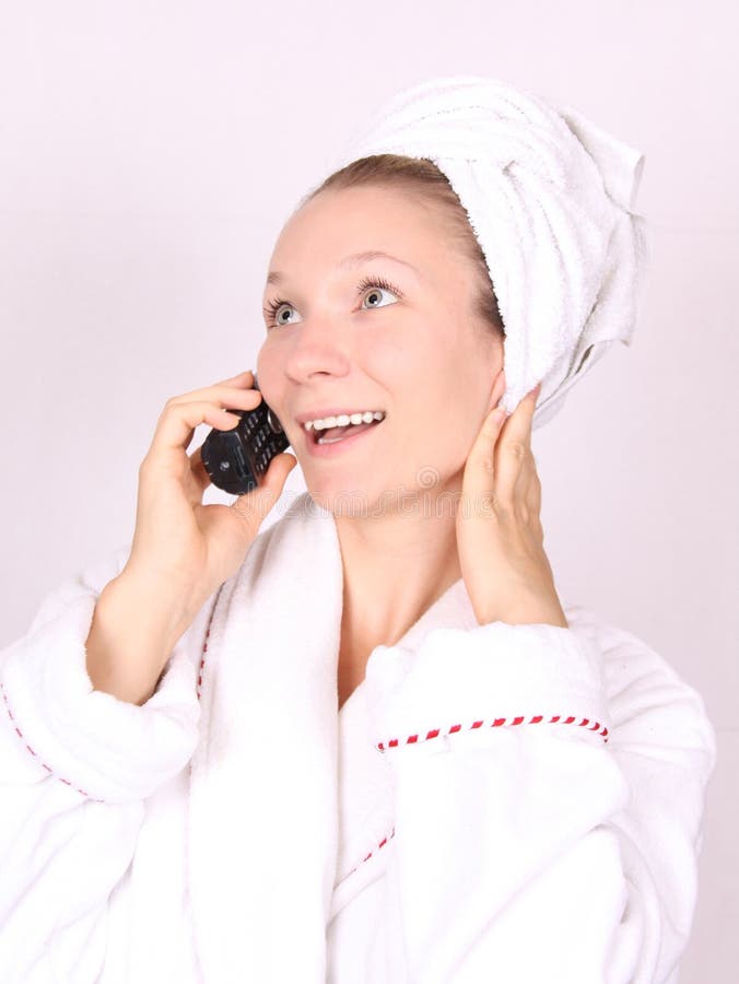 Woman in white bathrobe talks on telephone