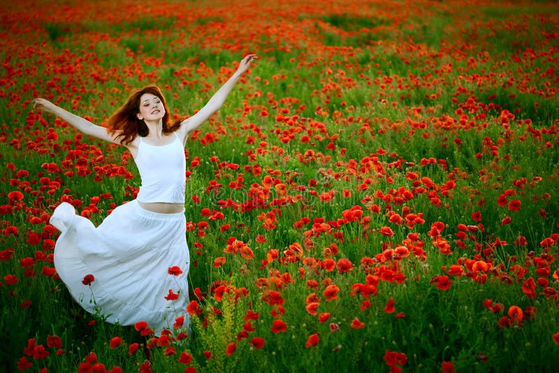 Woman in white dress running poppy field