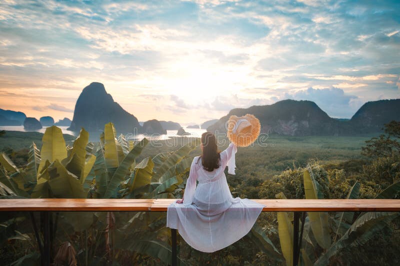 Woman with the white dress sit and see the mountain in early morning at Samet Nangshe viewpoint in Andaman sea on morning cloudy