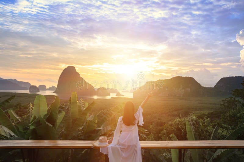 Woman with the white dress sit and see the mountain in early morning  at Samet Nangshe viewpoint in Andaman sea on morning cloudy