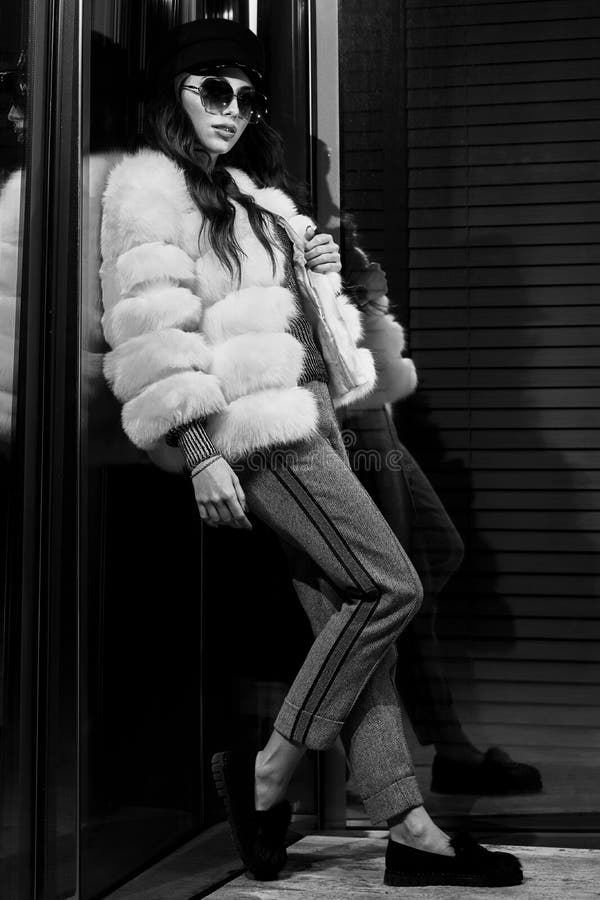 Woman in white fur coat standing with her back leaning on glass royalty free stock photography Woman in white fur coat standing with her back leaning on glass royalty free stock photography