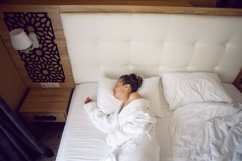 Woman in White Robe is Lying on the Bed and Sleeping Near Window in
