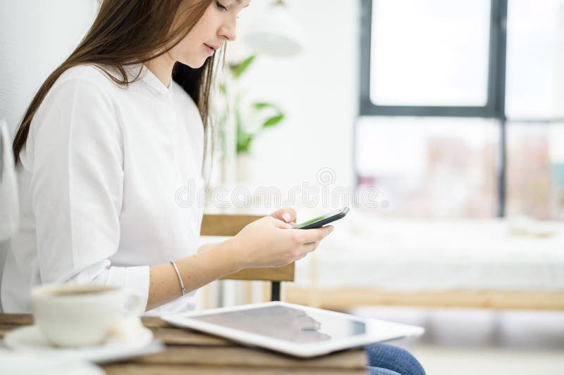 A woman in a white shirt is drinking coffee in a cafe. A female office worker at a lunch break solves a business problem