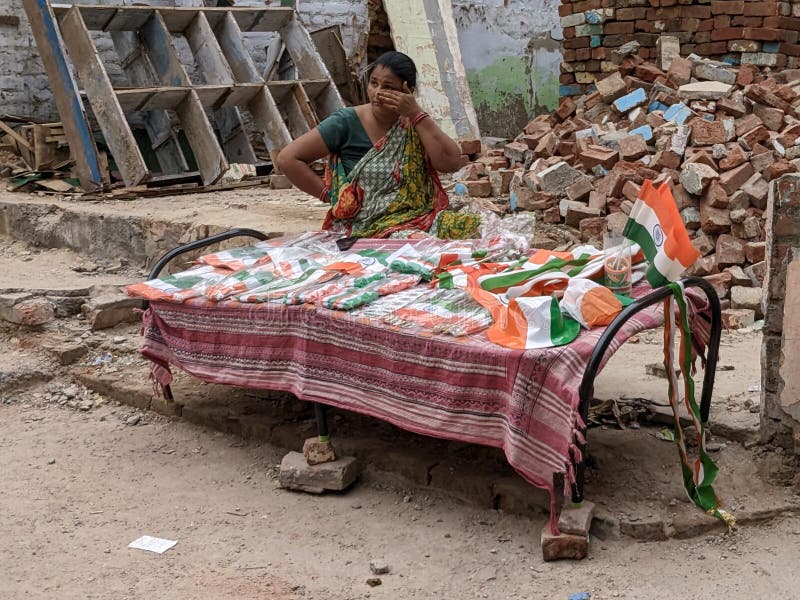 This is a woman who is selling tricolour flags and hats as the patriotic theme on the eve of Independence Day festival. She is working very hard. This image was taken at Shahpur Jat in New Delhi. This is a woman who is selling tricolour flags and hats as the patriotic theme on the eve of Independence Day festival. She is working very hard. This image was taken at Shahpur Jat in New Delhi.