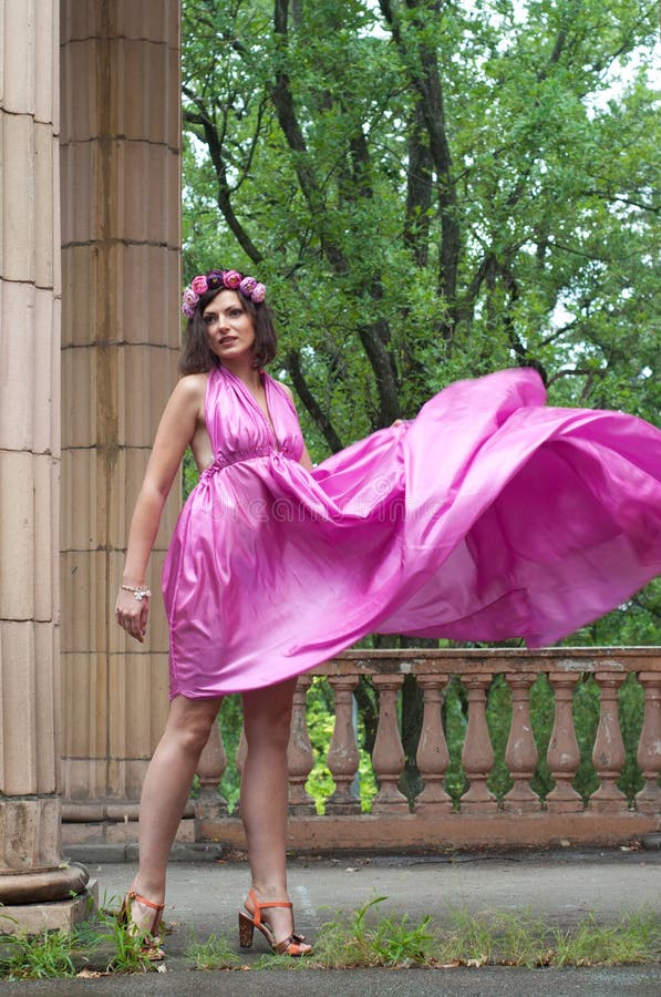 Beautiful young woman model wearing pink violet silk tunic dress, moving as...