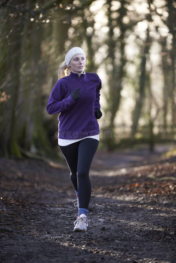 Woman On Winter Run Through Woodland