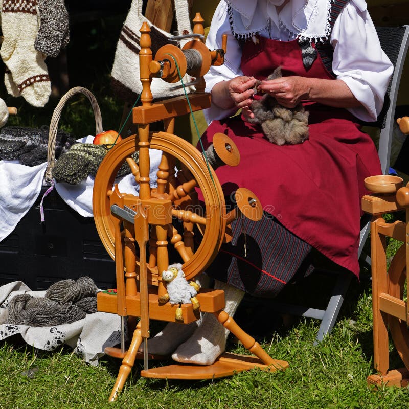 This Woman In Action Is Making Homemade Yarn With A Spinning Wheel From Raw  Wool For A Unique Hand Crafted Work. Shot In A Beautiful Garden Setting.  Stock Photo, Picture and Royalty