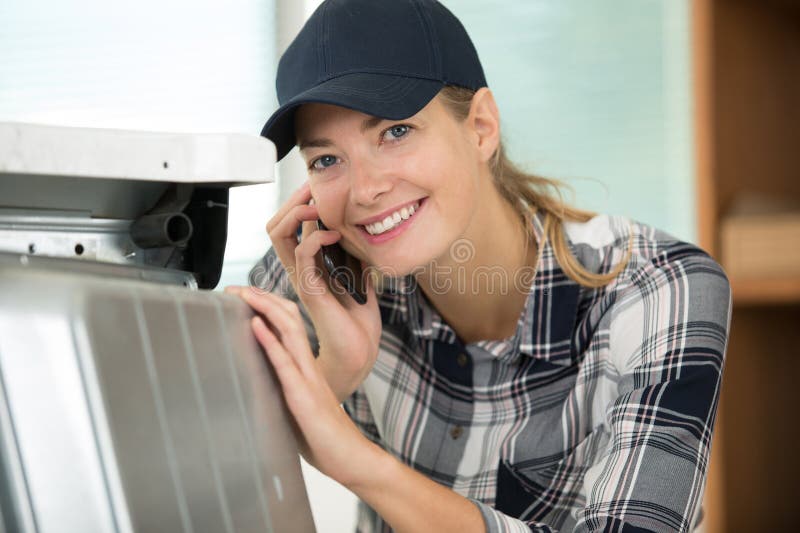 Woman worker in metal workshop on phone stock photo