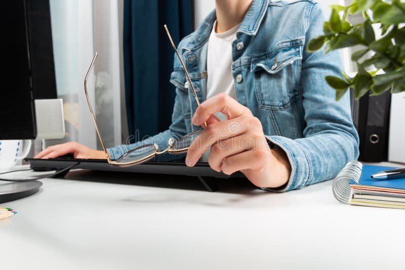 Woman working at her home office, hipster girl freelance writing on computer and holding glasses in her hand. Business concept stock photo Woman working at her home office, hipster girl freelance writing on computer and holding glasses in her hand. Business concept stock photo