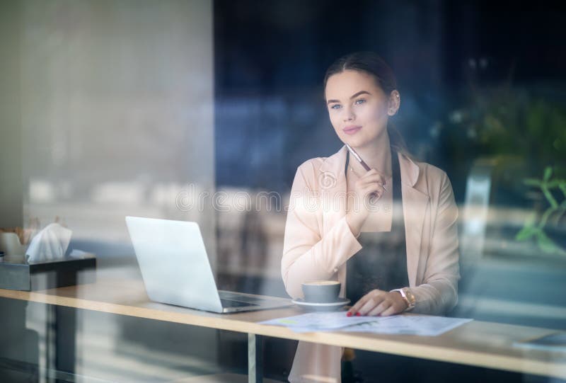 Woman working on laptop at coffee shop. Window Reflexions. Shot of a young woman using a laptop in a cafe royalty free stock images Woman working on laptop at coffee shop. Window Reflexions. Shot of a young woman using a laptop in a cafe royalty free stock images