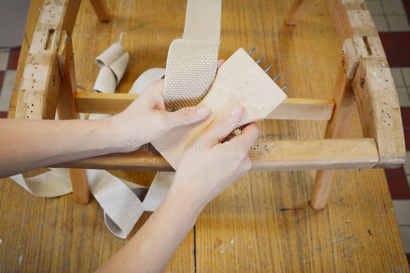 Woman Working in Upholstery Workshop with Webbing Stretcher. Stock