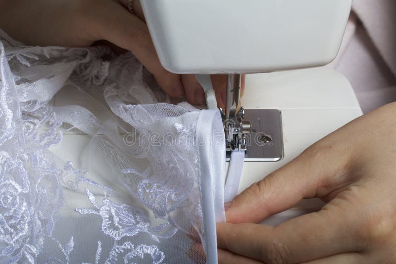 A Woman Works on a Sewing Machine. Sewing of Lace Fabric. Stock Photo