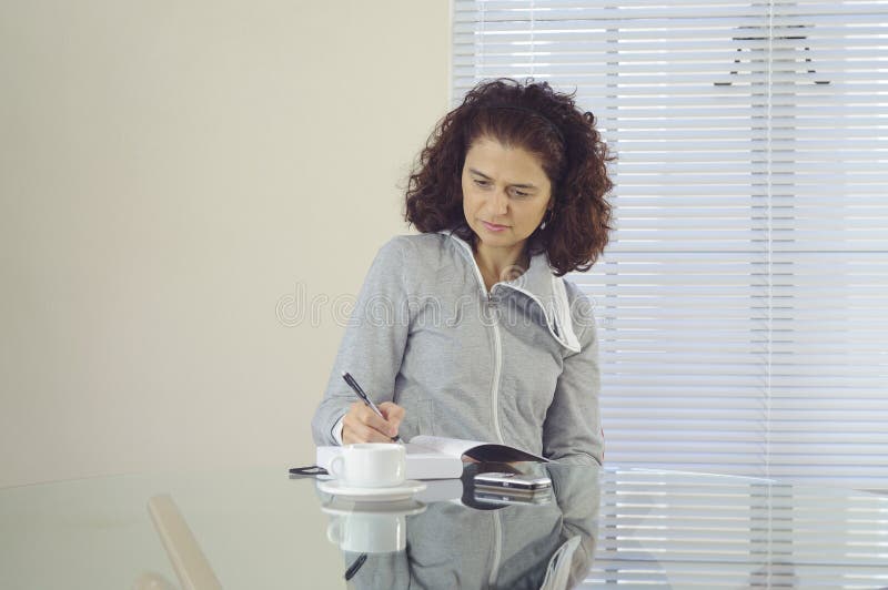 Una donna sul bicchiere tavolo suo rivista.