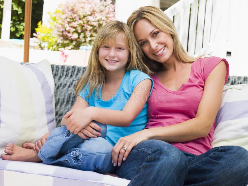 Woman and young girl sitting on patio smiling