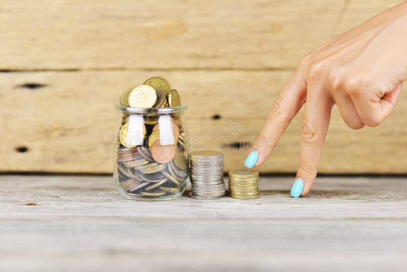 Womanâ€™s fingers climbing stairs of money to a full of money transparent jar, financial growth concept stock image