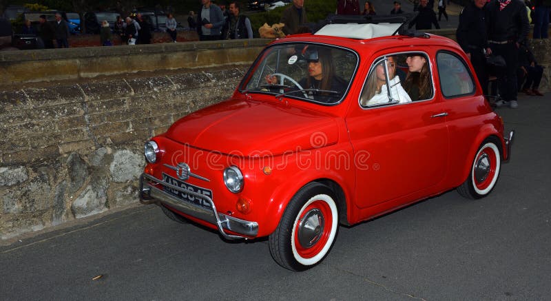 Classic Red Fiat 500 motor car with picnic basket parked on