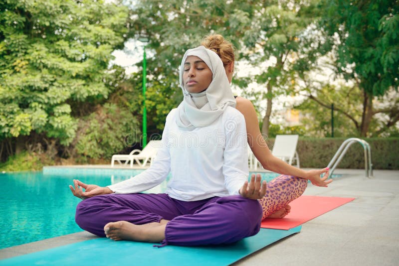 Women doing yoga by the poolside