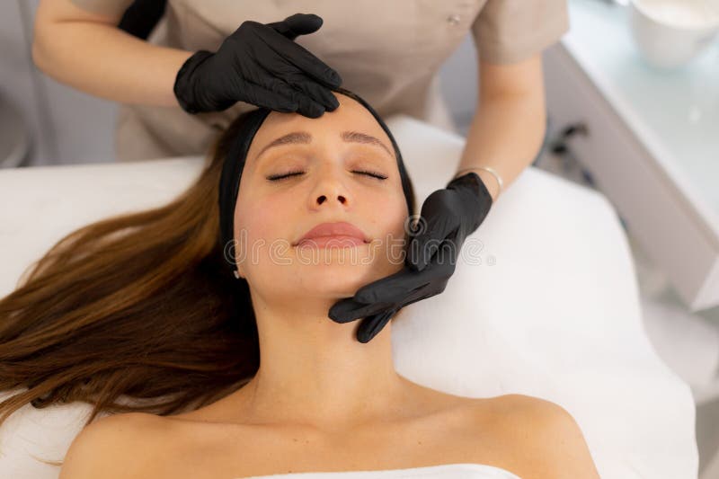 A women enjoys a peaceful facial treatment in a tranquil spa setting, surrounded by calming colors and gentle hands providing a revitalizing experience. Pampering experience stock images, royalty-free photos and pictures