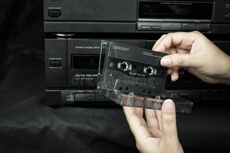 women hand holding a cassette tape compact at old played audio tape background