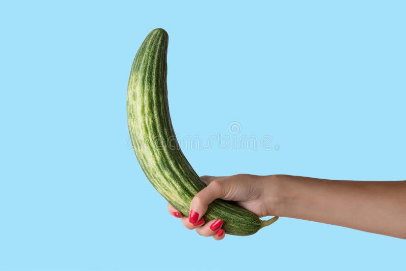 Women hand holding cucumber like a man`s penis on blue background. Erotic concept stock photography Women hand holding cucumber like a man`s penis on blue background. Erotic concept stock photography