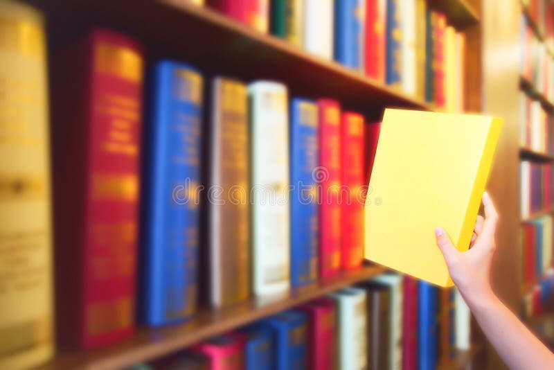 Women hand pulling yellow book from wood bookshelves in public library. Colorful books, Textbook, Literature on bookshelf. Women hand pulling yellow book from royalty free stock photos