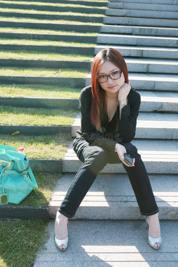 Women holding mobile phone sitting on stair