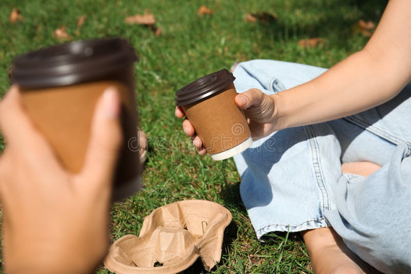 Women holding takeaway cardboard coffee cups with plastic lids outdoors, closeup royalty free stock images