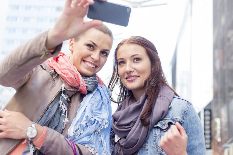 Women in jackets taking self portrait through mobile phone