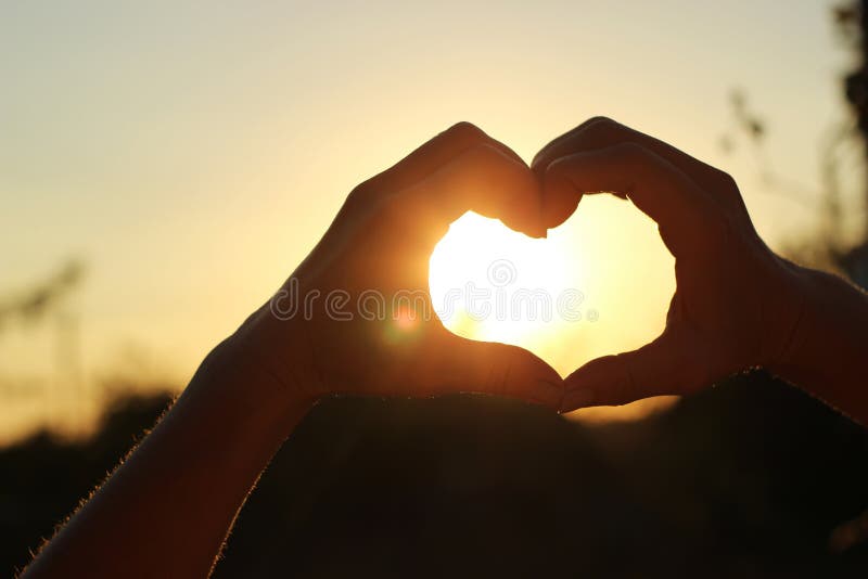 Women& x27; las manos de s se cruzan bajo la forma de corazón a través del cual el sun& x27; los rayos hacen la manera en la pues fotografía de archivo Women& x27; las manos de s se cruzan bajo la forma de corazón a través del cual el sun& x27; los rayos hacen la manera en la pues fotografía de archivo