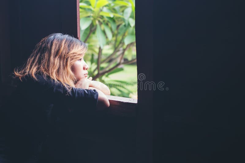 Women lifestyle concept : young sad woman sitting on bench beside window look to outside, sadness,loneliness.