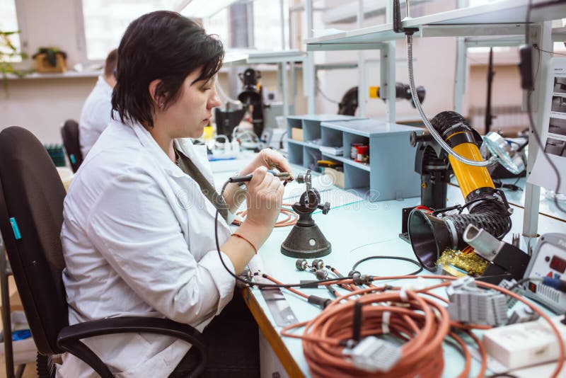 Women make soldering of radio components to electronic boards. Plant for the production of electronic equipment.