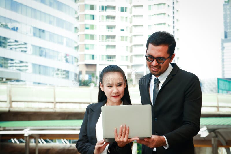 Business women and men wear suits to wear notebook computers. Women and men wearing suits Holding a notebook computer Talk, do business together royalty free stock images Business women and men wear suits to wear notebook computers. Women and men wearing suits Holding a notebook computer Talk, do business together royalty free stock images