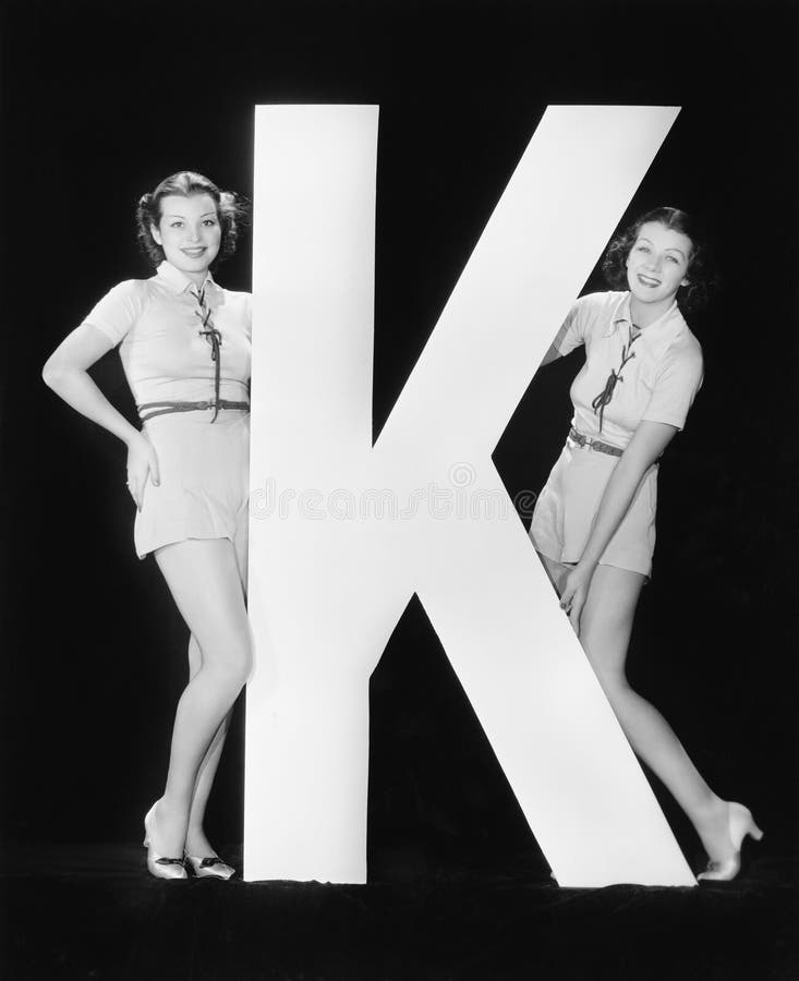 Women posing with huge letter K