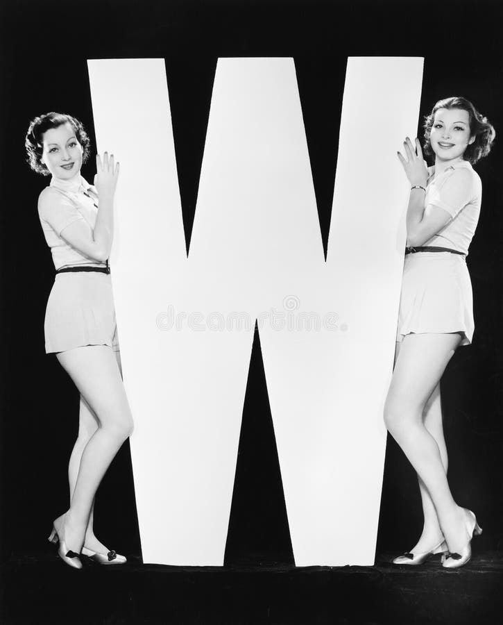Women posing with huge letter W
