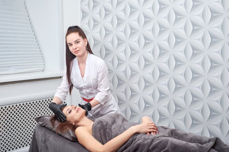 A woman prepares for a hair removal procedure with a photoepilator in the salon royalty free stock photo A woman prepares for a hair removal procedure with a photoepilator in the salon royalty free stock photo