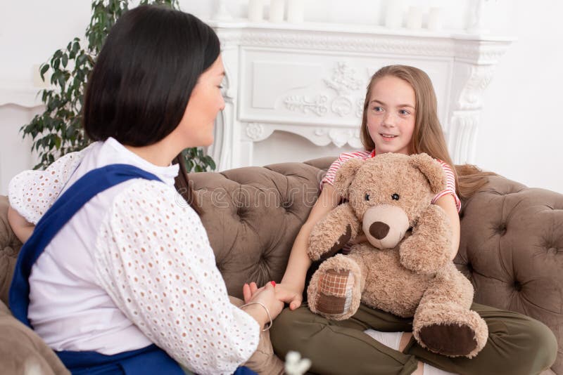 A woman is a professional child psychologist talking with a teenage girl in her cozy office. Psychological assistance to children