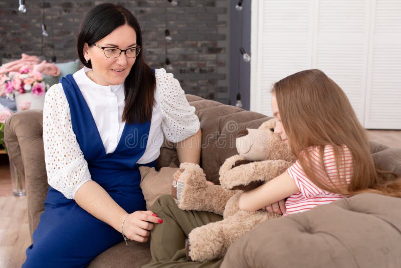 A woman is a professional child psychologist talking with a teenage girl in her cozy office. Psychological assistance to children