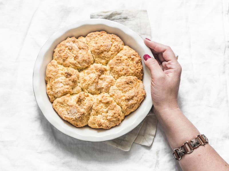 Women`s hand holding baking dish with freshly baked homemade breakfast rolls on light background royalty free stock photography Women`s hand holding baking dish with freshly baked homemade breakfast rolls on light background royalty free stock photography