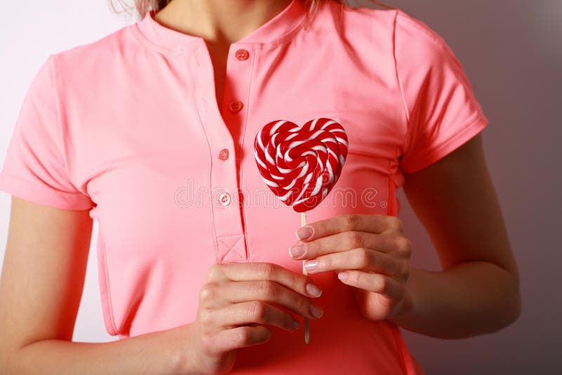 Women`s hands holding a lollipop in the shape of heart. Gift for