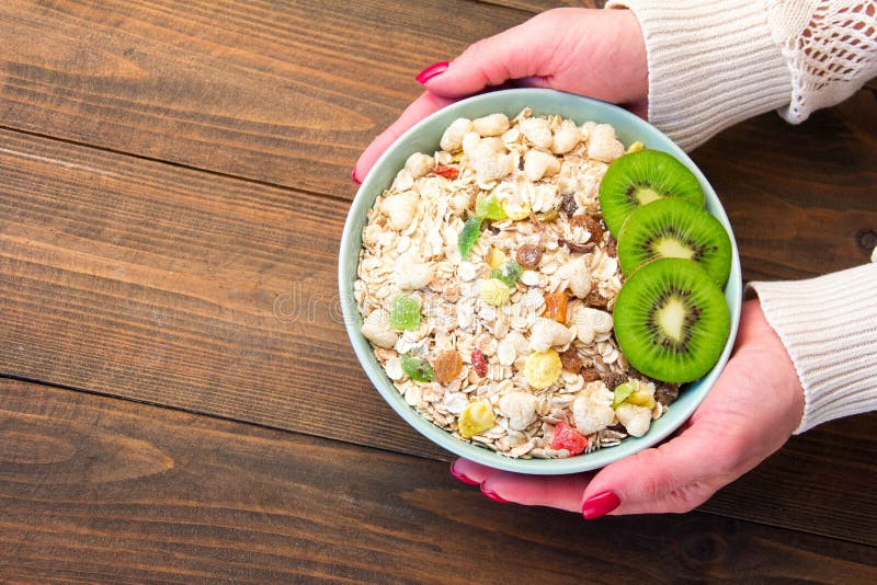 Women`s hands offer a healthy breakfast cereal muesli with dried fruits royalty free stock photo