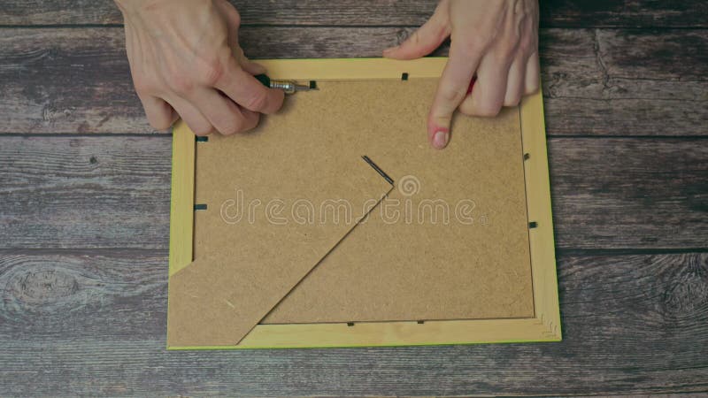 Women's hands with a screwdriver open a frame for a photo, a home interior, a woman is independent.