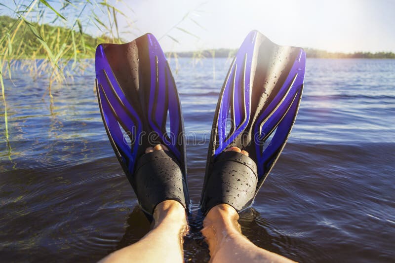 Women`s legs in flippers by the lake on a hot summer day stock images Women`s legs in flippers by the lake on a hot summer day stock images