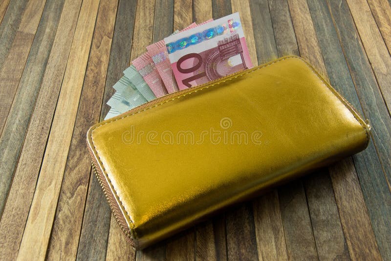 Women`s money purse with gold color on wooden background