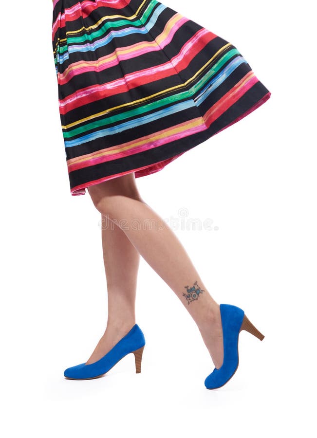 Donna multicolore vestito e gambe in blu tacchi alti e drum kit tatuaggio sulla gamba.