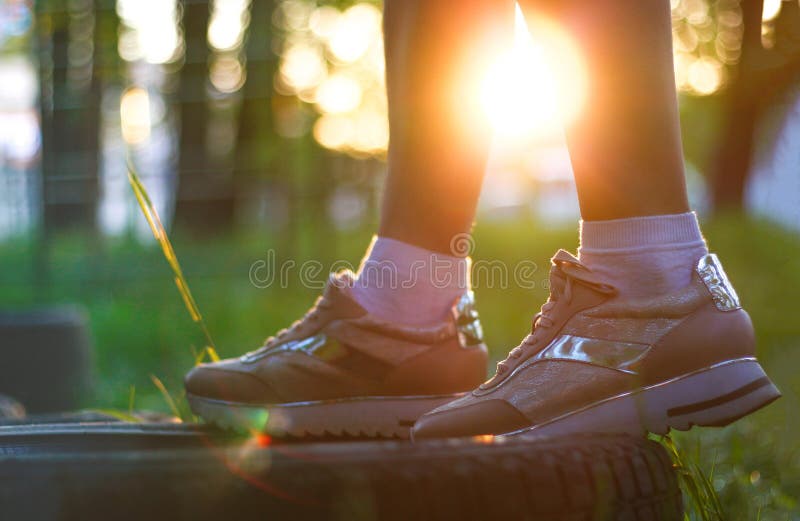 Women`s sports shoes at sunset. Sneakers in the Sunny forest.