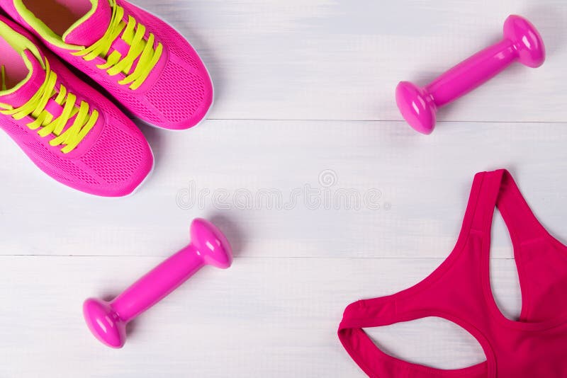 Womens sportswear, with pink dumbbells, on a light wooden floor