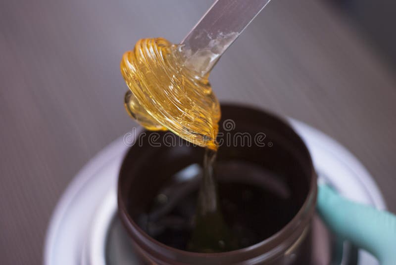 A women takes out from the jar a Pasta for a Sugaring, Yellow color. Depilatory sugar paste. Beauty and cosmetics.